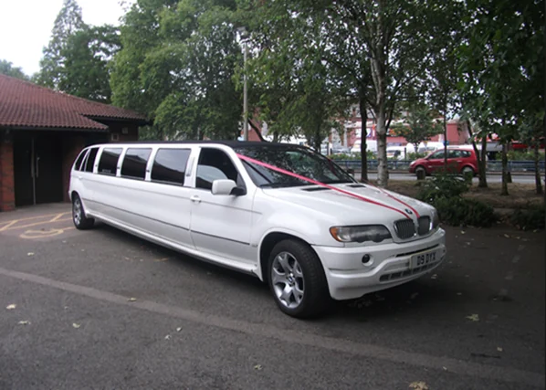White BMW X5 stretch limousine decorated with pink ribbons