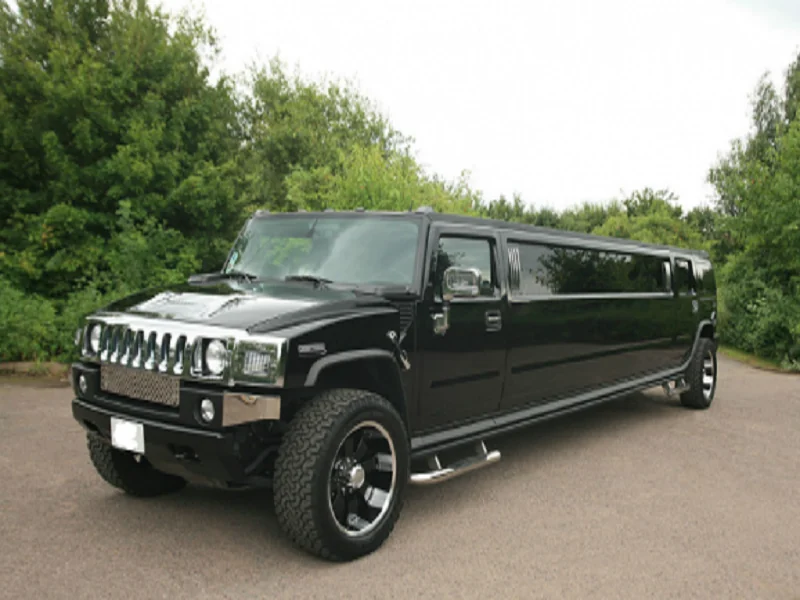 Black Hummer stretch limousine parked beside trees